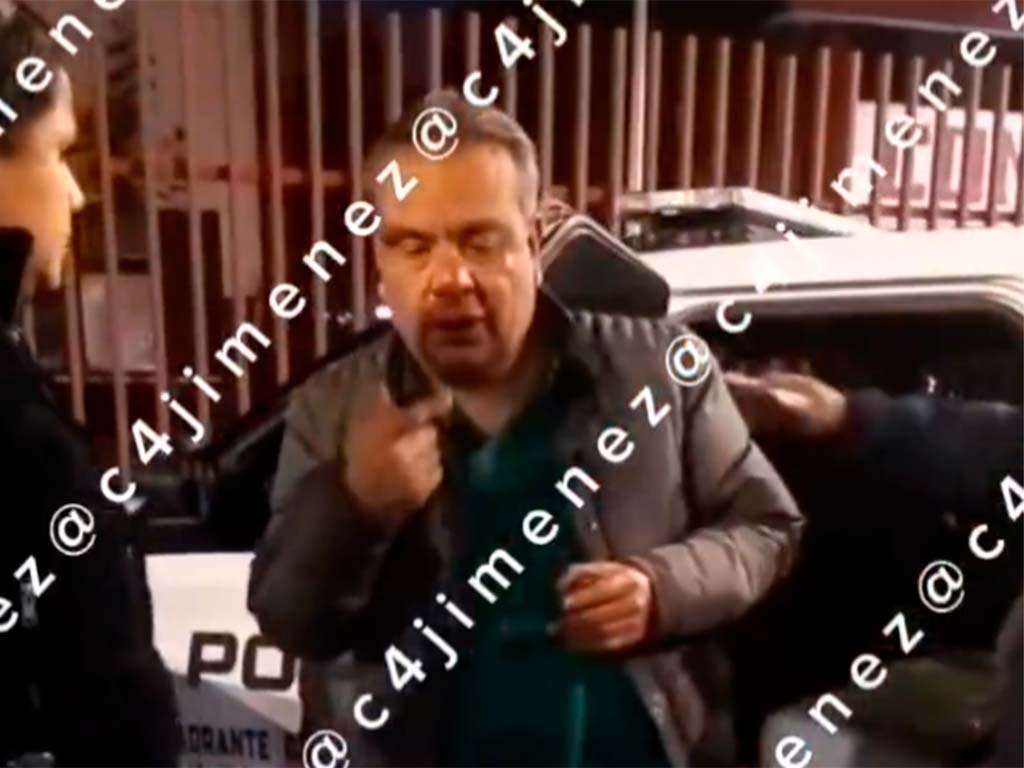 Funcionario detenido en Azcapotzalco tambaleándose mientras policías lo aseguran tras chocar presuntamente ebrio contra un taxi.
